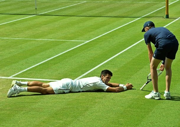 Novak Djokovic lies in the grass